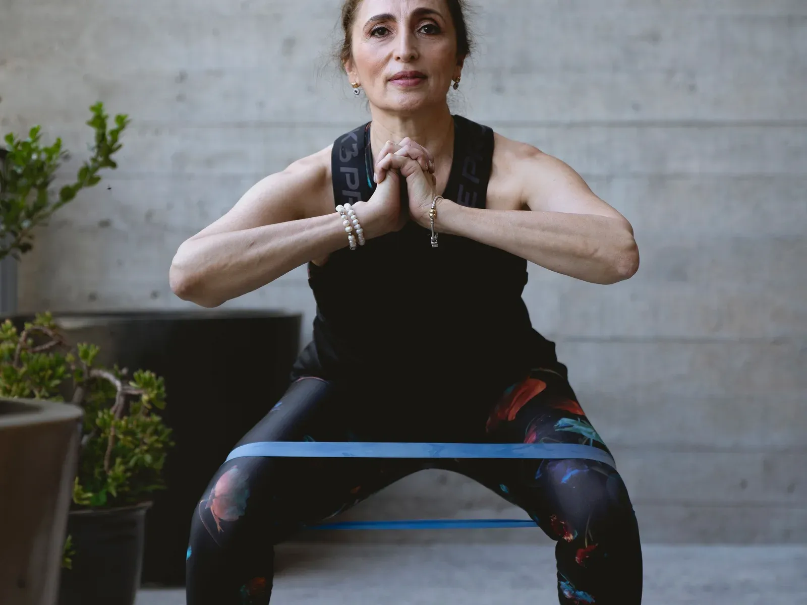 A woman in her fifties holding a wide squat with a resistance band around her thighs